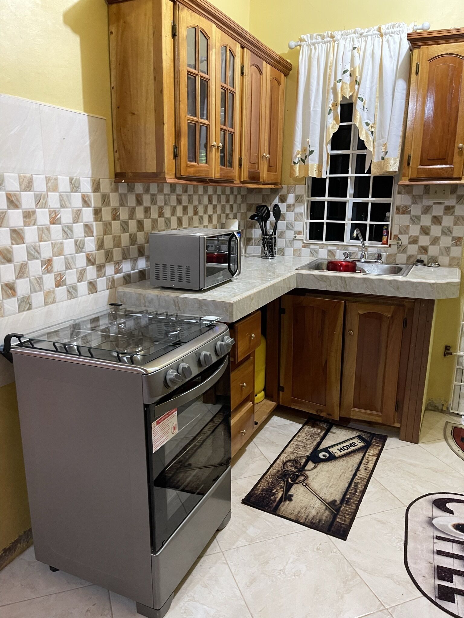 A kitchen with wooden cabinets, a microwave, a gas stove, and a sink.