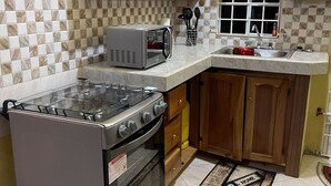 Cucina con mobili in legno, forno a microonde, piano cottura a gas e lavello.