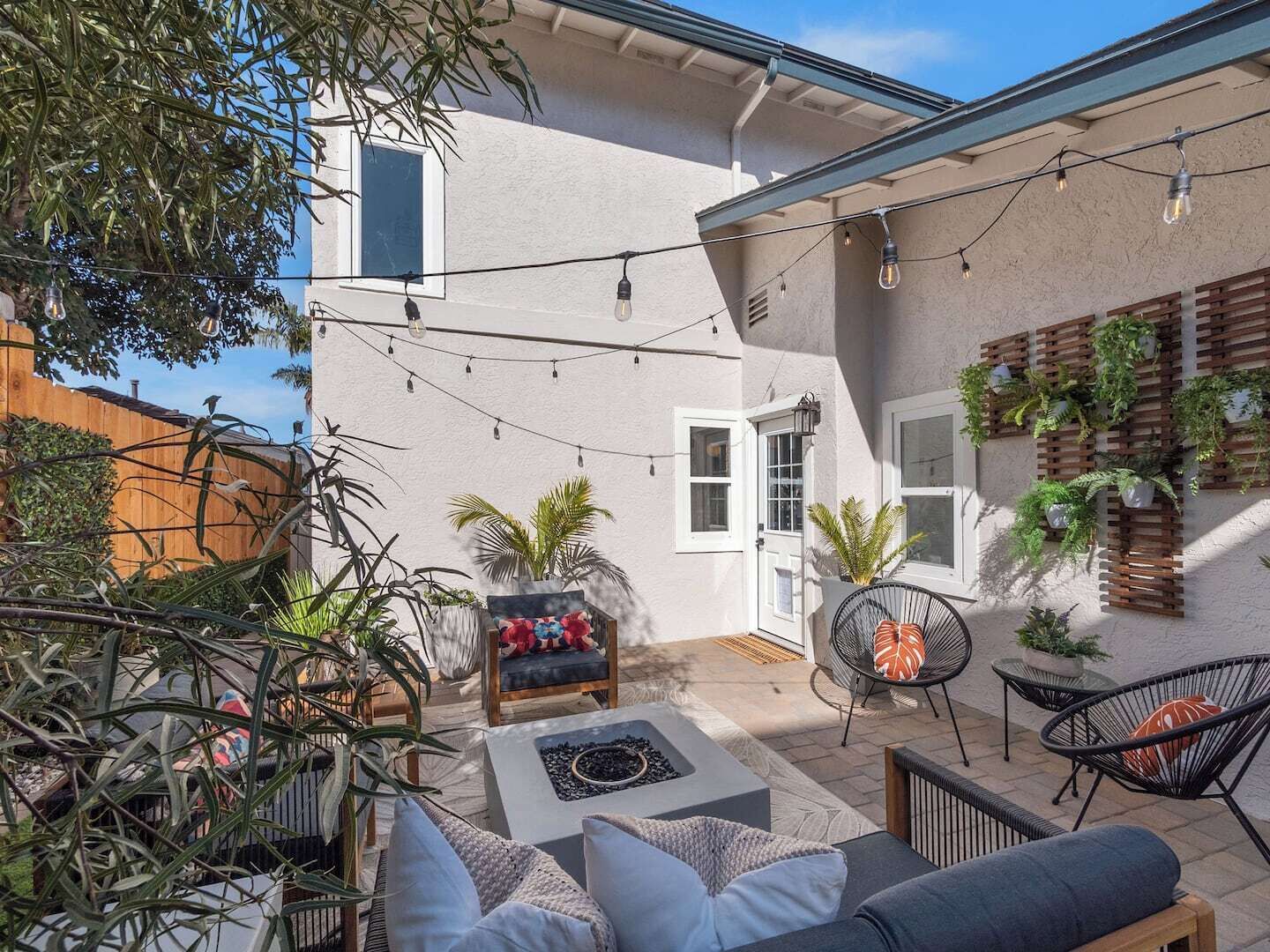 A patio with outdoor furniture, string lights, and potted plants.