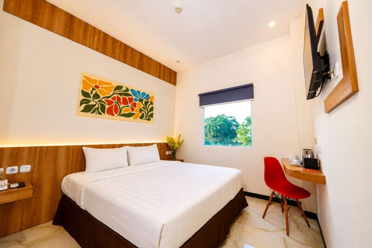 Une chambre d’hôtel équipée d’un lit, d’un bureau, d’une chaise, d’une fenêtre et d’un téléviseur fixé au mur.