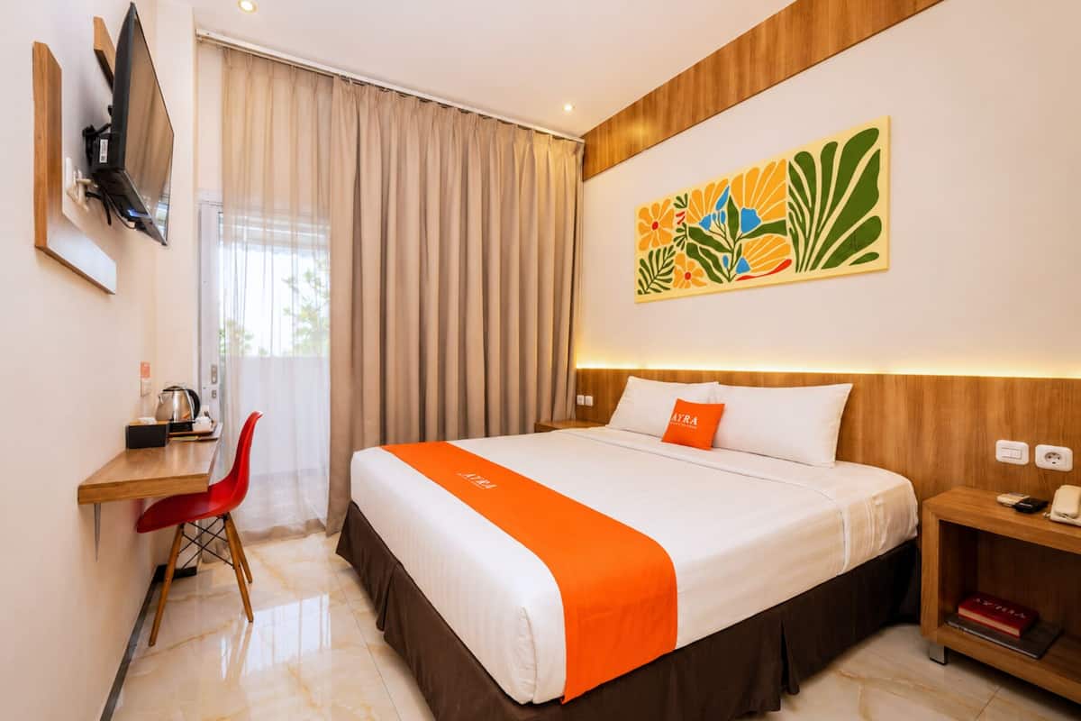 Une chambre d’hôtel équipée d’un lit, d’un bureau, d’une chaise, d’une télévision et d’une œuvre d’art murale.