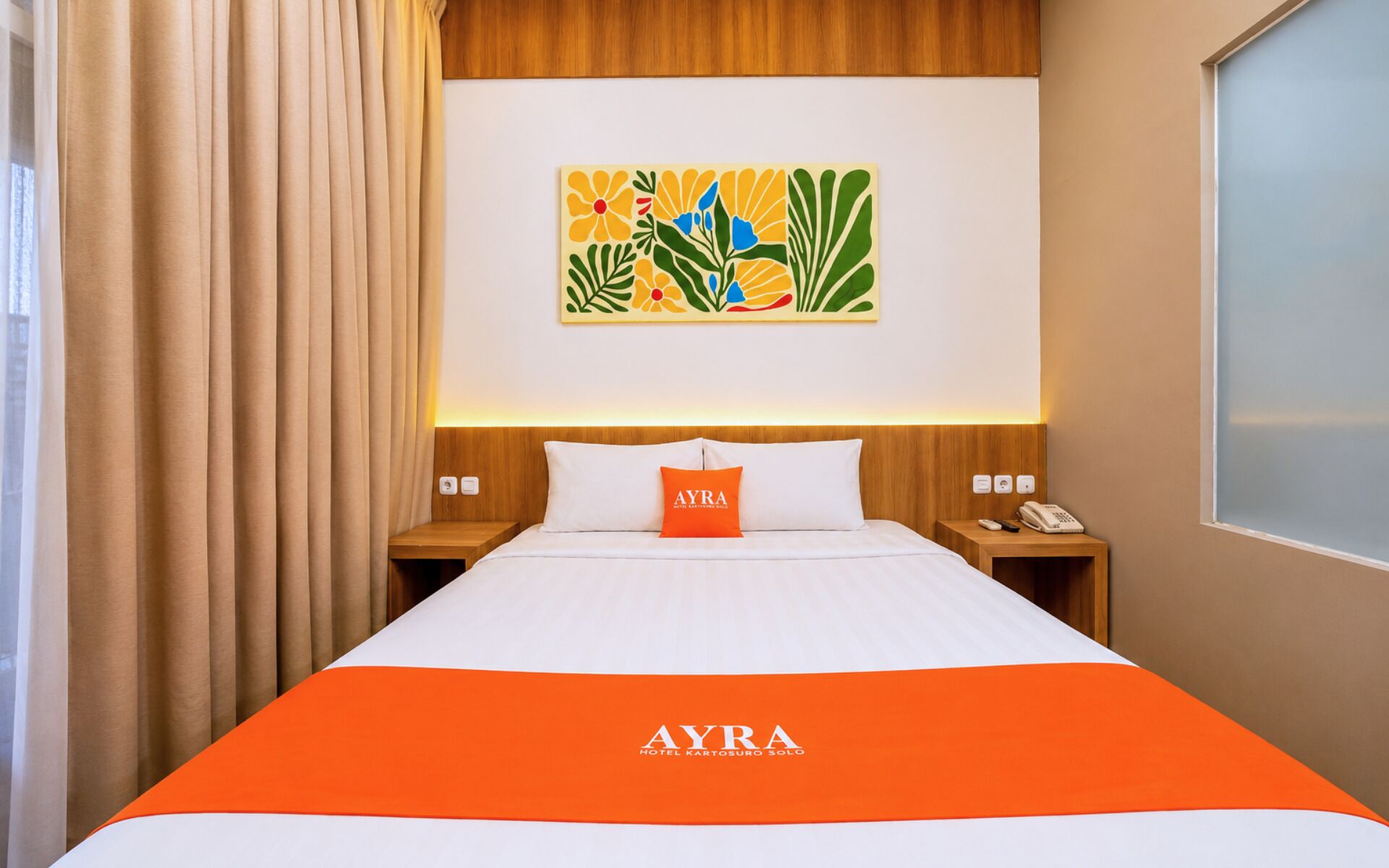 A hotel room with a bed, a nightstand, a telephone, and a wall art piece.