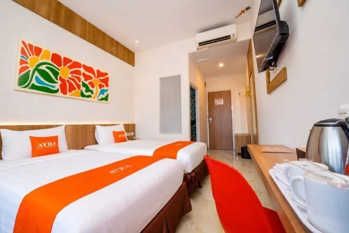 Une chambre d’hôtel avec deux lits, une télévision, une machine à café et un tableau au mur.