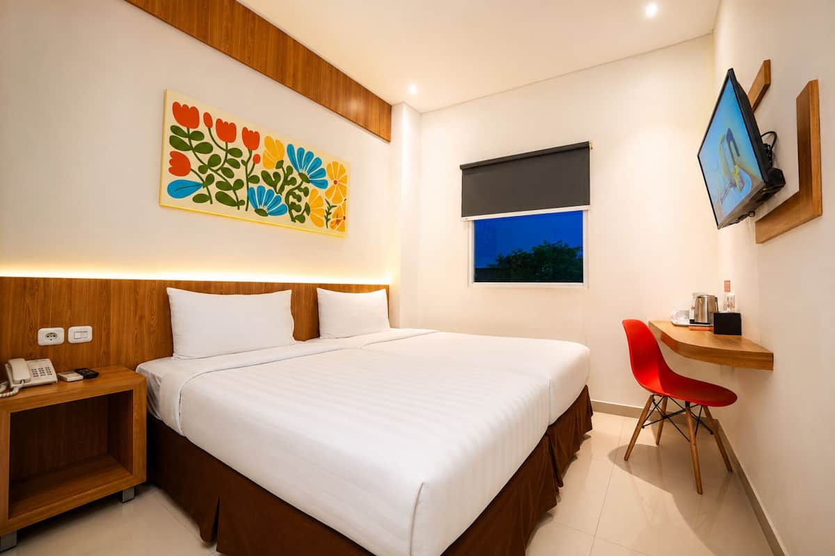 Une chambre d’hôtel comprenant un lit, une table de chevet, une télévision, un bureau avec une chaise et une fenêtre.