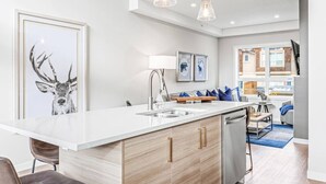 A modern kitchen with a large island, stainless steel appliances, and pendant lighting. - Brand New 3BR with Mountain views & Private garage (Canmore)