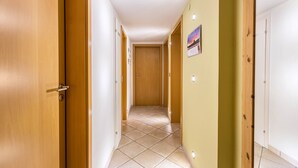 A hallway with wooden doors, a tiled floor, and a wall-mounted picture. - Apartment 'Schwarzwaldblick' with Mountain View, Balcony, and Wi-Fi (St.Georgen im Schwarzwald)