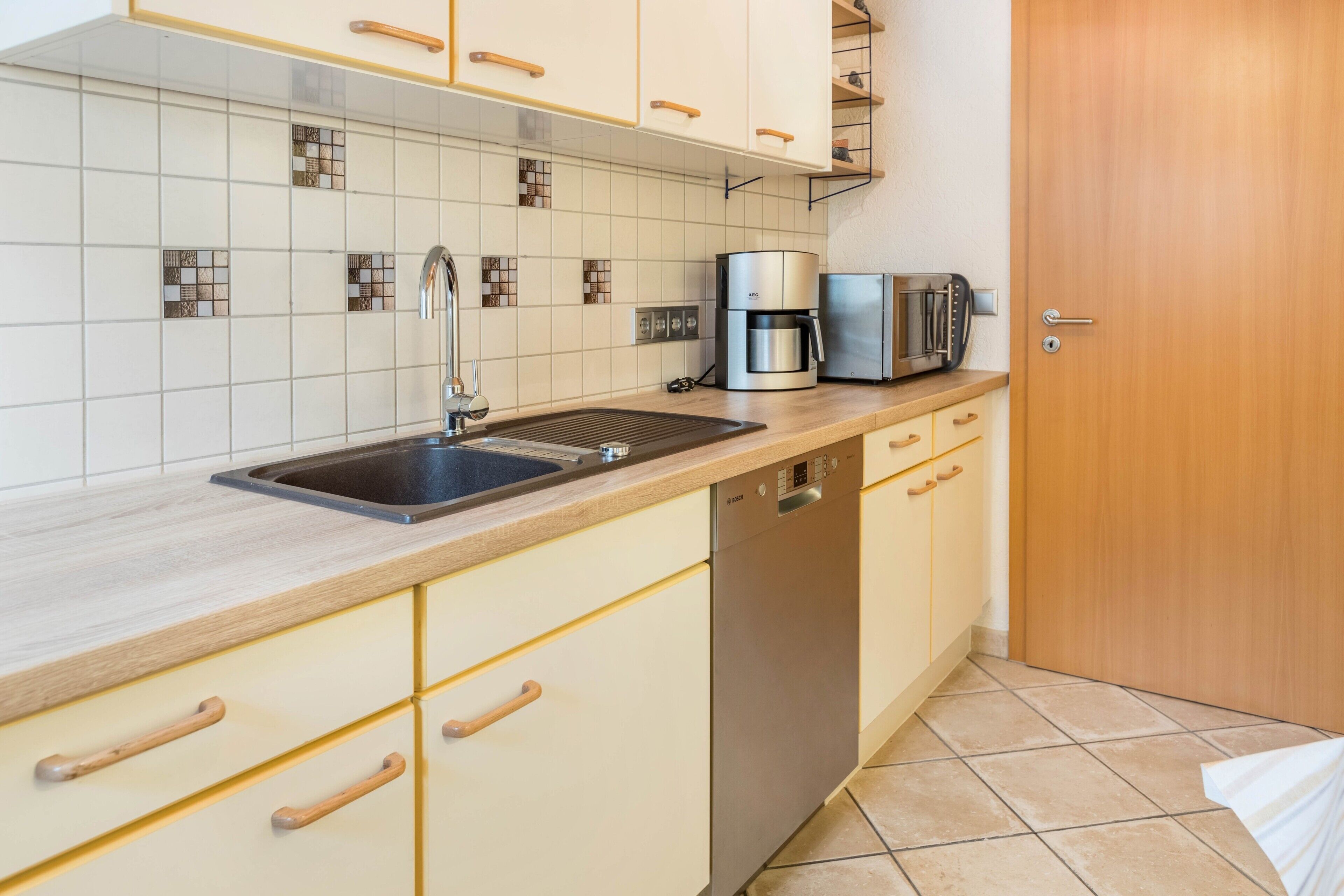 Una cocina equipada con lavaplatos, cafetera, tostadora y pileta.