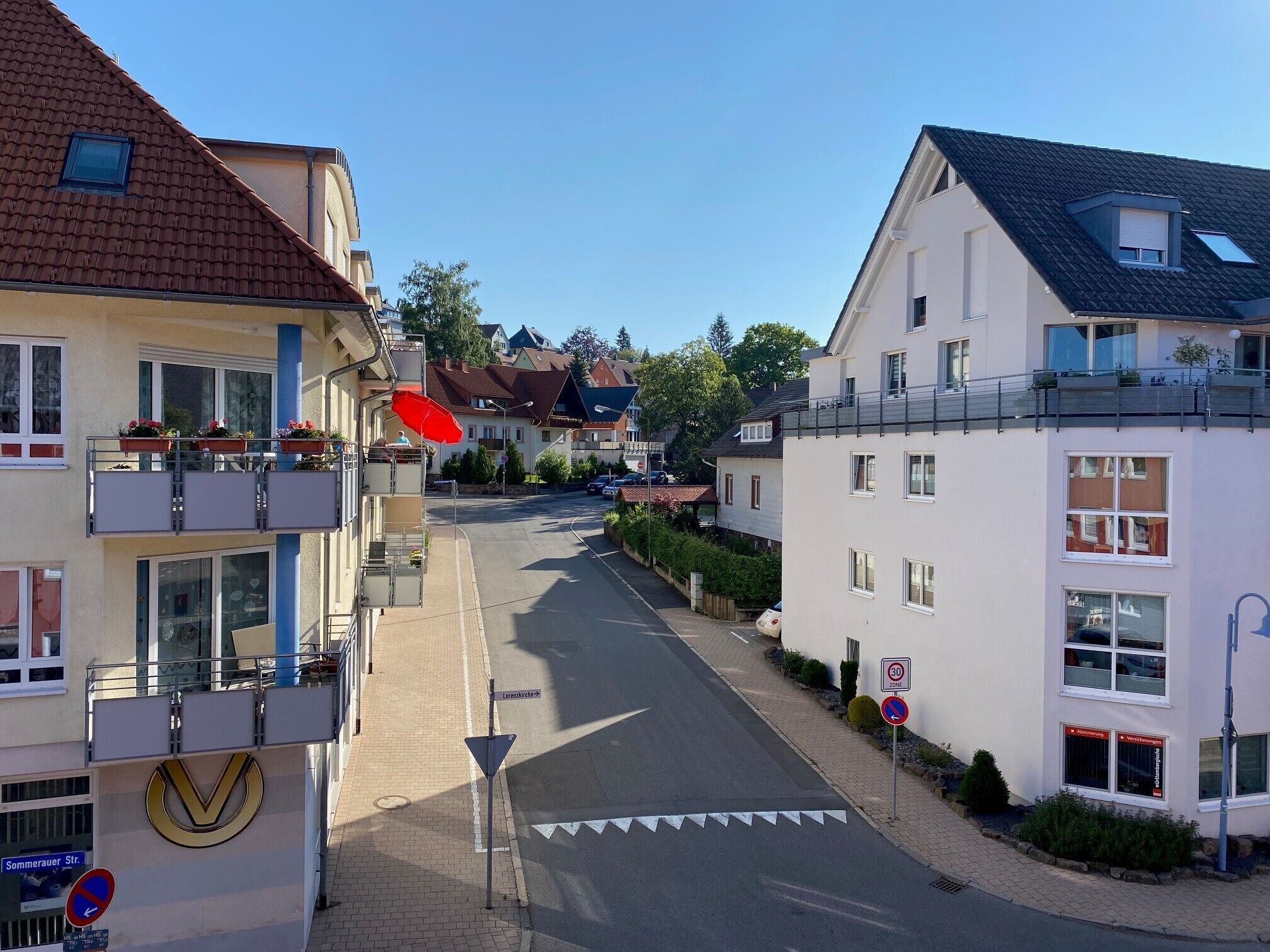 A street view with buildings, a no parking sign, and a pedestrian crossing.
