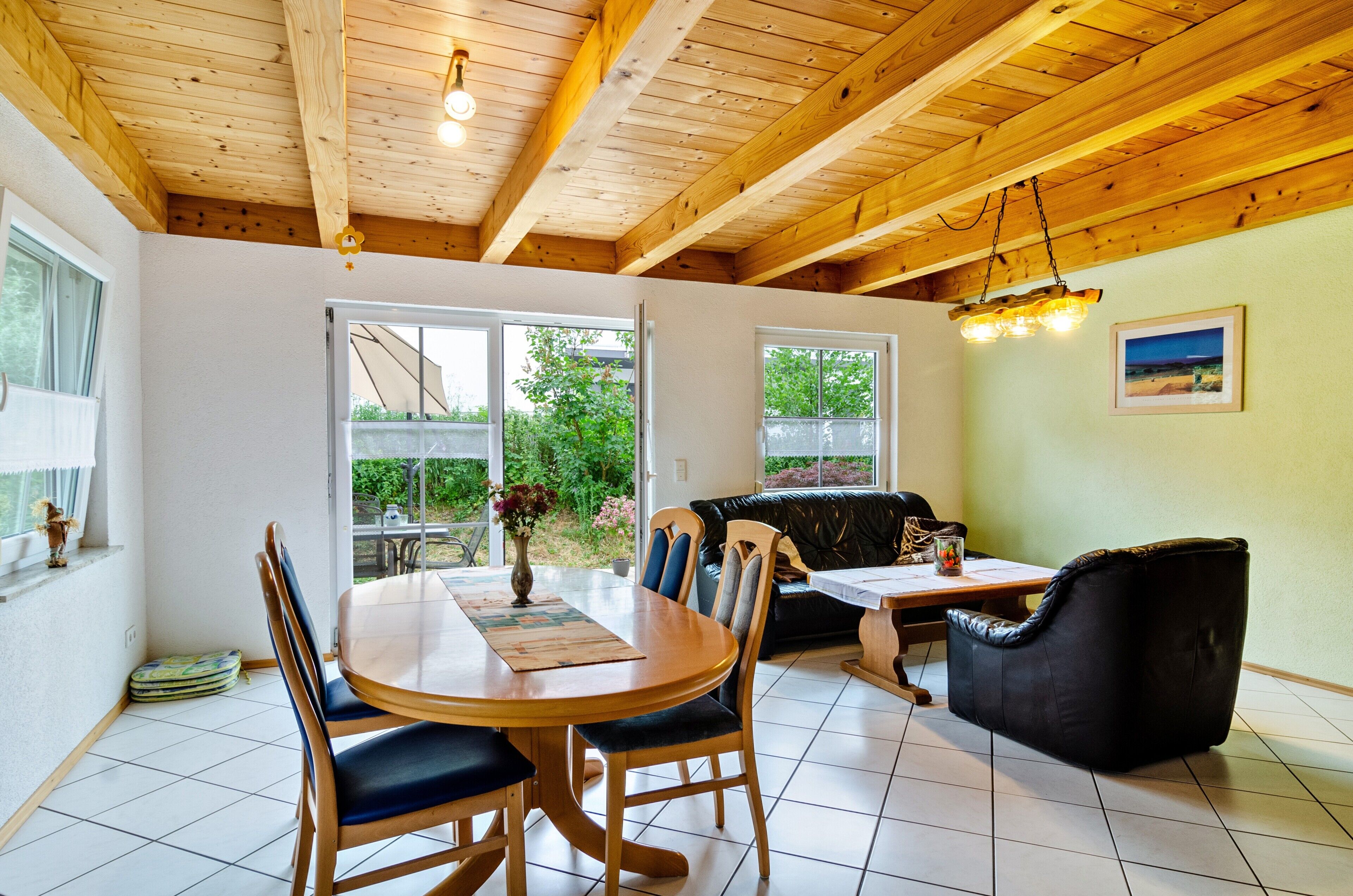Ein Essbereich mit Holztisch und -stühlen, einer Couch und einer Decke mit freiliegenden Balken.