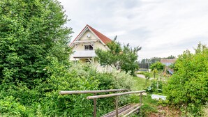 Ein Haus, umgeben von üppigem Grün, einem Holzzaun und einem klaren Himmel.