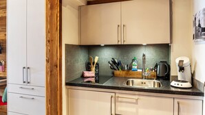 A kitchen with white cabinets, a black countertop, and a coffee machine.