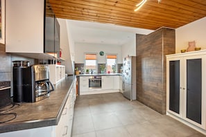A modern kitchen with a coffee maker, oven, and refrigerator. - Apartment "Elli" with Mountain View, Shared Garden & Wi-Fi (Aulendorf)