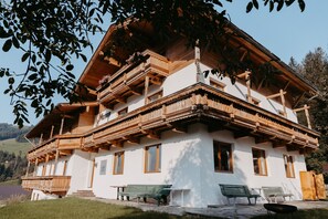 Una xalet de fusta tradicional amb un balcó, diverses finestres i seients exteriors.