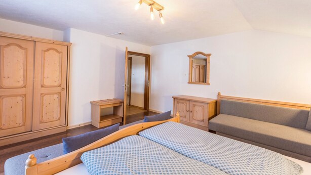 A bedroom with a bed, a sofa, a wardrobe, and a mirror. - Krafttal Kelchsau – Where New Energy Awaits (Kelchsau)