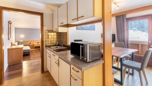 Una cocina compacta con microondas, armarios de madera y una zona de comedor con mesa y sillas.