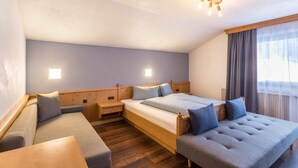 Un dormitorio con una cama, un sofá, una mesita y una ventana con cortinas.