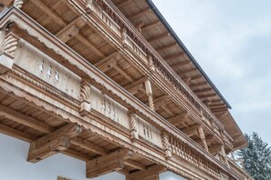 A wooden balcony with intricate carvings and a sloped roof.