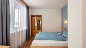 A bedroom with a wooden bed, a nightstand, a mirror, and a view of a hallway. - Krafttal Kelchsau – Where Nature Gives You Strength and Every Moment Feels Like Home (Kelchsau)