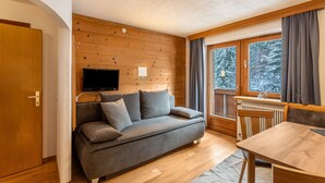 Une pièce chaleureuse avec un canapé, une table et un téléviseur fixé à un mur en bois.