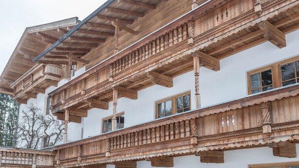 Un immeuble à plusieurs étages doté de balcons en bois, de grandes fenêtres et d’une façade blanche.