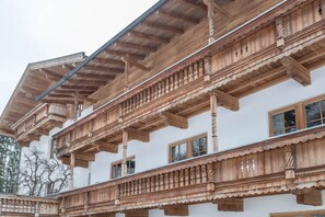 Ein mehrstöckiges Gebäude mit Holzbalkonen, großen Fenstern und einer weißen Fassade.