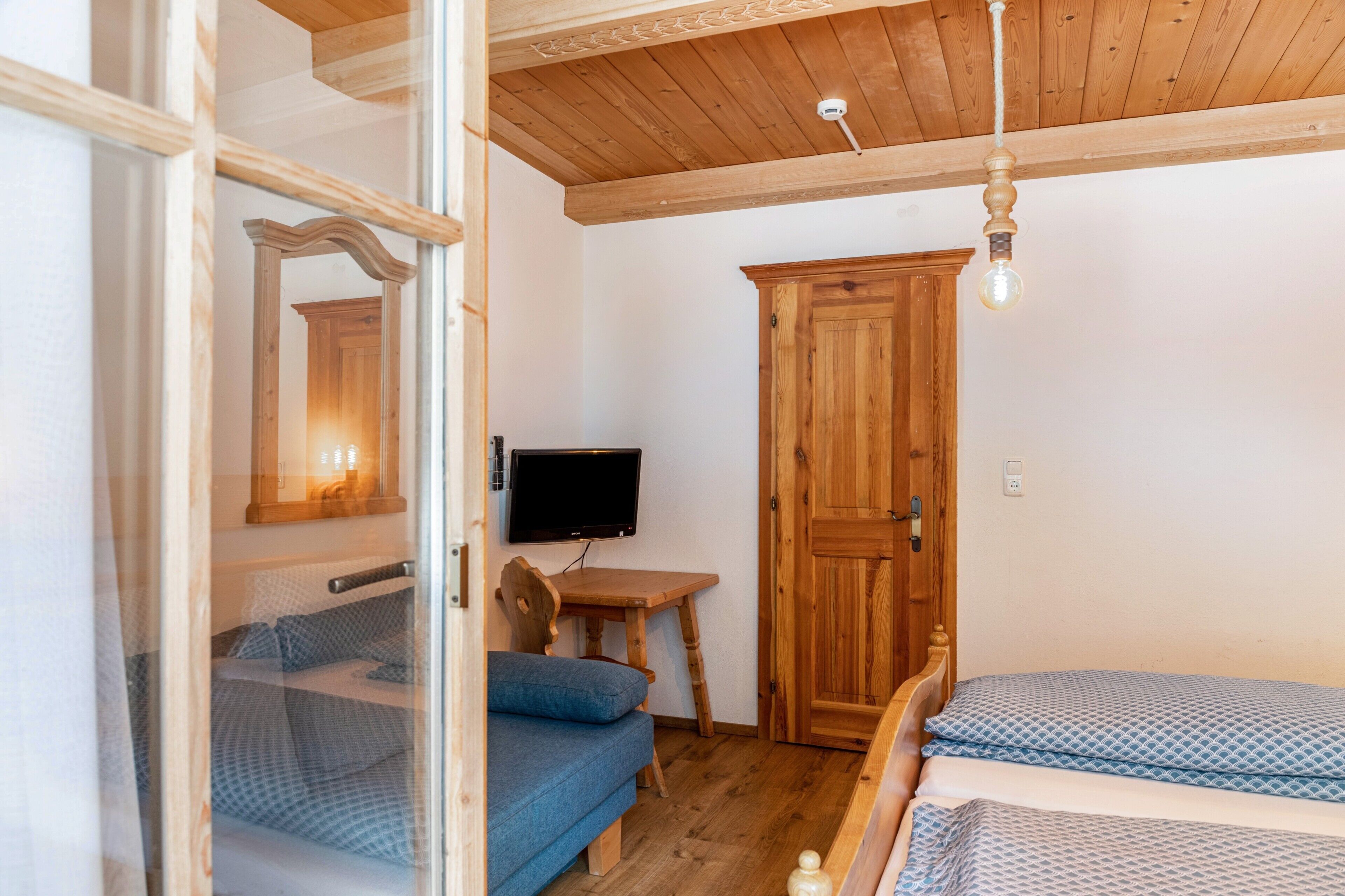 Une chambre à coucher avec un lit, une armoire en bois, une télévision et une petite table.