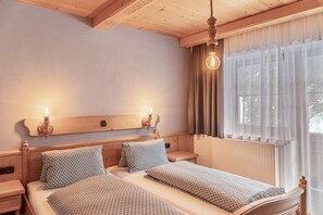 A double bed with patterned bedding, wooden headboard, bedside tables, and a light fixture.