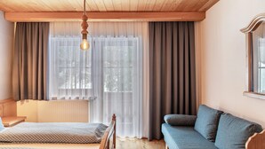 Una stanza con un letto, un divano, un soffitto in legno e una finestra con tende.