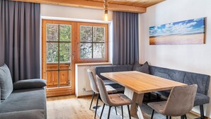 A dining area with a wooden table, grey sofa, and a painting on the wall.