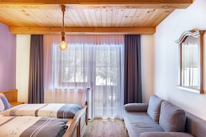 A room with a bed, a sofa, a wooden ceiling, a window with curtains, and a hanging light fixture. - Holiday Apartment "Schwüwong - Apartment 13" with Mountain View, Shared Terrace and Wi-Fi (Kelchsau)