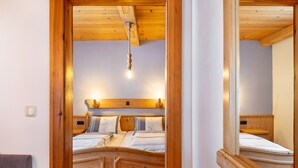 A wooden-framed bedroom with a bed, bedside tables, and a hanging light fixture.