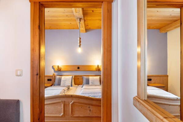 A wooden-framed bedroom with a bed, bedside tables, and a hanging light fixture.