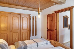 A wooden bedroom with a bed, wardrobe, and a hanging light fixture.