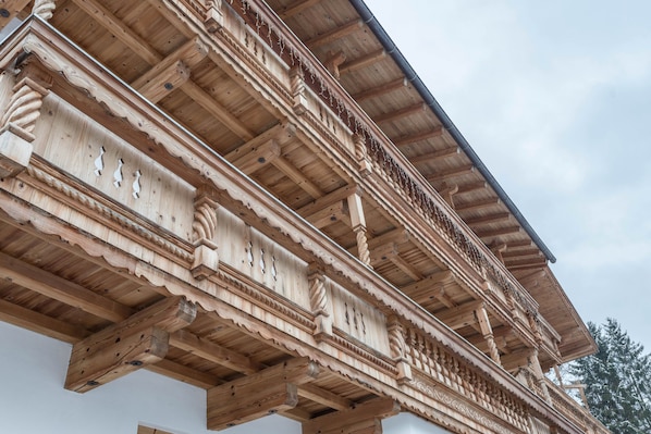 A detailed wooden balcony with intricate carvings and a sturdy roof structure.