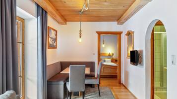 Een modern interieur met een houten plafond, een zithoek met een tafel en stoelen, een bed en een douchegedeelte.