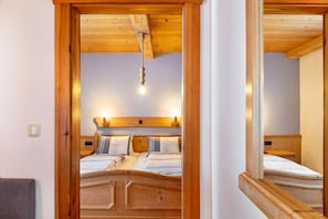 A wooden-framed bedroom with a bed, bedside lamps, and a hanging light fixture.