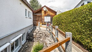 Une cabane en bois avec un mur en pierre et une haie.