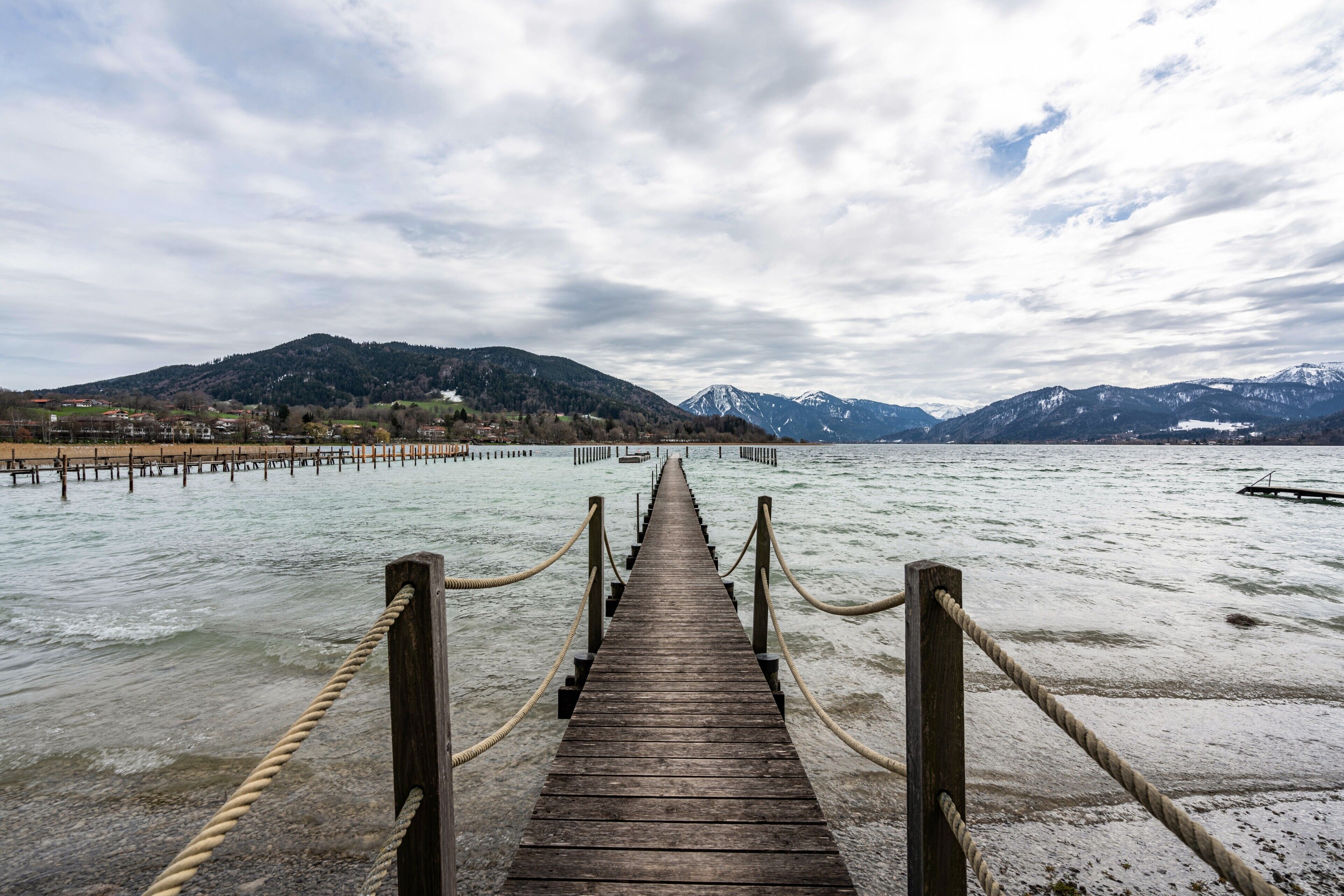 A wooden pier leading to a body of water with mountains in the background.