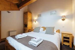 Een slaapkamer met een groot bed, twee nachtkastjes, een houten garderobe en wandlampen.