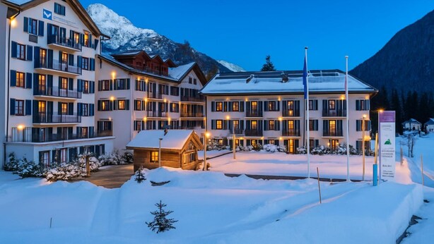 A multi-story hotel with balconies, a wooden cabin, and a snowy landscape with mountains in the background. - V Buet 53: Beside Ski Lift; Pool, Sauna & Gym, Vallorcine (Argentiere), France (Vallorcine (Argentiere))