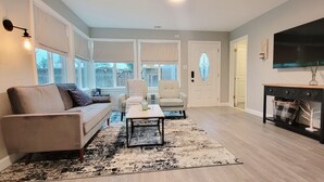 Una sala de estar con sofá, sillones, una mesa de centro, chimenea y televisor.