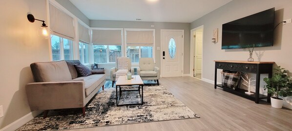 A living room with a sofa, armchairs, a coffee table, a fireplace, and a TV.