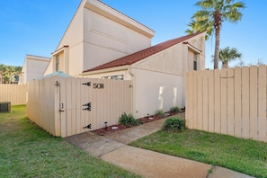 A single-story house with a beige exterior, a red-tiled roof, and a wooden fence.