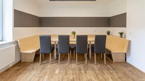 A modern dining area with a long wooden table, six chairs, and a ceiling light fixture.