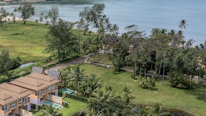 Um resort com vários edifícios, piscina e vista para o mar e colinas.