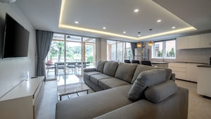 Uma sala de estar moderna com um sofá, uma TV e um espaço de jantar com mesa e cadeiras.