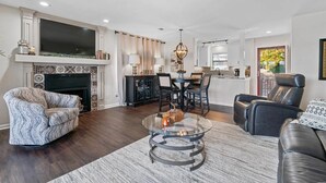 Una sala de estar moderna con chimenea, comedor y cocina.