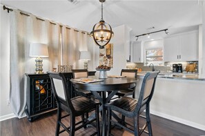 A dining area with a round table, four chairs, a chandelier, and a cabinet with a lamp. - NEW!!! The Boaty Hole - Boat Slip Included!! (Hot Springs)