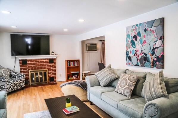 A living room with a fireplace, a sofa, a coffee table, and a bookshelf. - Sunset House Near Sunday River Black Mountain (Rumford)