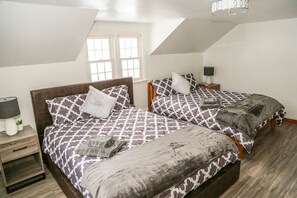 A bedroom with two beds, a nightstand, a lamp, and a window. - Sunset House Near Sunday River Black Mountain (Rumford)